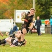 Rugby players tackle on a grassy field during a match at Crusaders Rugby Club in Oakville.