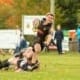 Rugby players tackle on a grassy field during a match at Crusaders Rugby Club in Oakville.