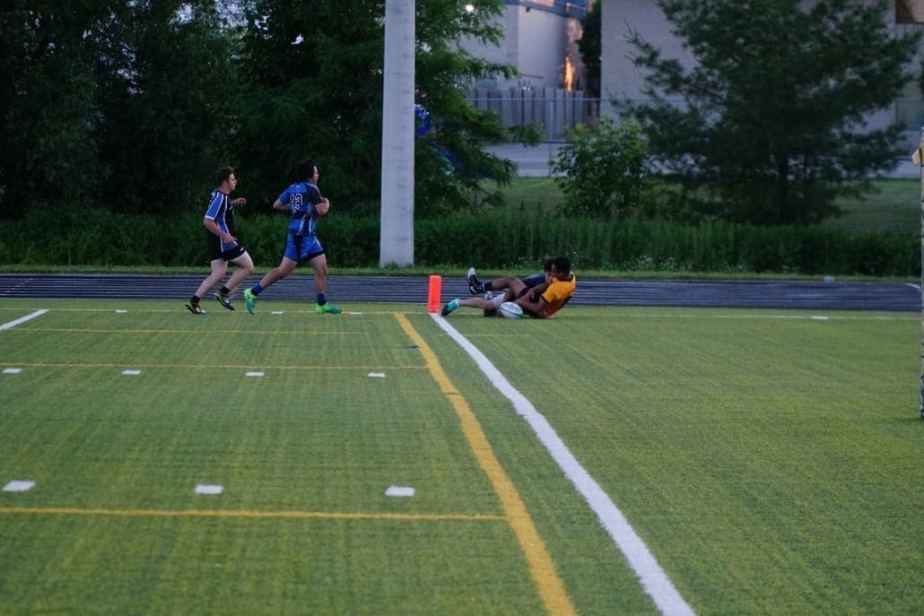 ORG_DSC09384 Crusaders Rugby Club players sprint on a green turf field in Oakville, while an injured player lies near the sideline.