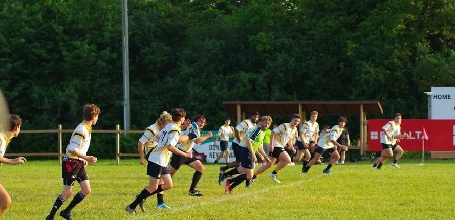 Aurora4 Crusaders Rugby Club players sprint across a grassy rugby field in Oakville during a match.