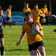 Crusaders Rugby Club players in yellow and blue jerseys play rugby on a grassy field in Oakville.