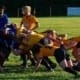 Rugby players from Crusaders Rugby Club in blue and yellow jerseys scrummaging on a grassy field in Oakville.