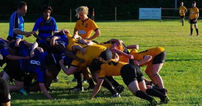 MT8 Rugby players from Crusaders Rugby Club in blue and yellow jerseys scrummaging on a grassy field in Oakville.