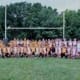 Group photo of the Crusaders Rugby Club in Oakville posing on a rugby field with goalposts in the background.