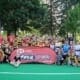 Group photo of Crusaders Rugby Club players and coaches in Oakville posing on a green field with a red Rookie Rugby banner.