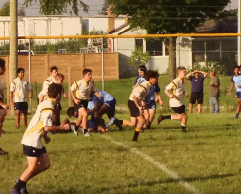 Youth rugby players from the Crusaders Rugby Club in Oakville compete on a grassy field.