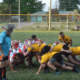 Rugby players in a scrum on a grassy field wearing red-and-white striped and yellow jerseys at Crusaders Rugby Club in Oakville.