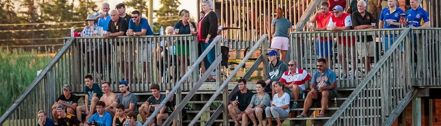 Crowd of spectators seated on metal bleachers watching a rugby match at Crusaders Rugby Club Oakville.