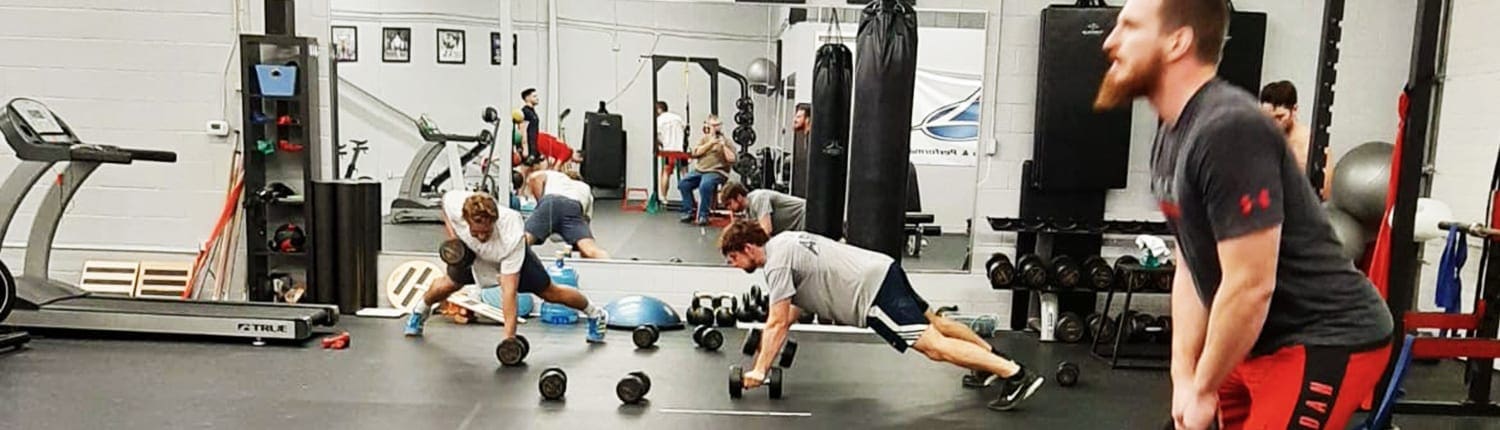 Crusaders Rugby Club Oakville players train in a gym, performing planks and other exercises.