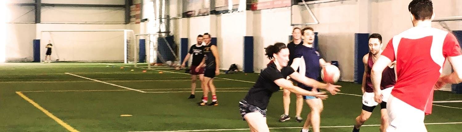 Rugby players practicing indoors on a turf field at Crusaders Rugby Club in Oakville.