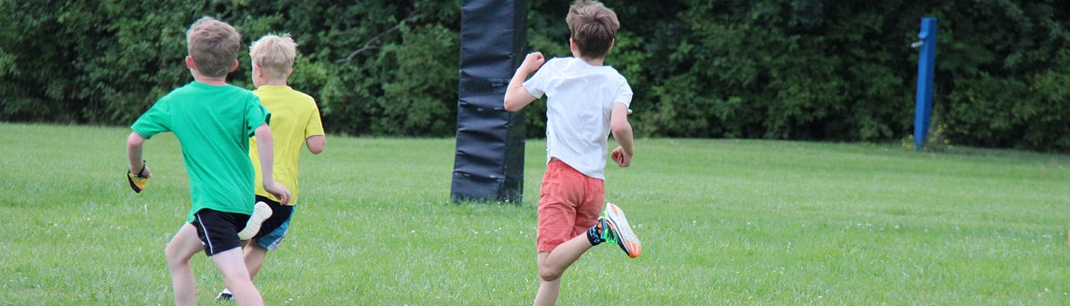 Three youth rugby players from the Crusaders Rugby Club in Oakville sprint on a grassy field. Three youth rugby players from the Crusaders Rugby Club in Oakville sprint on a grassy field.
