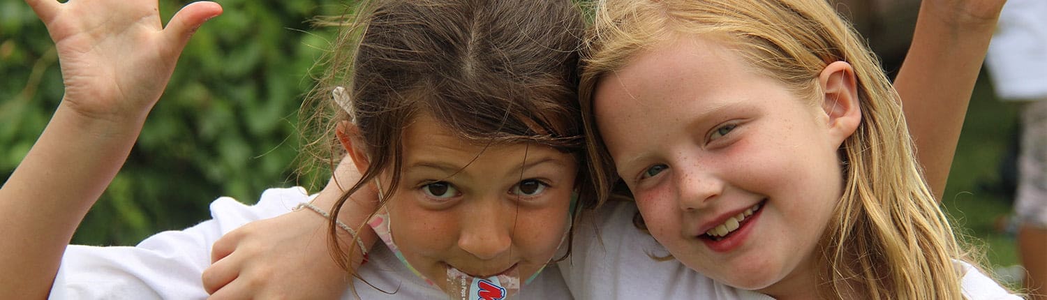 Two girls smiling and hugging outdoors at Crusaders Rugby Club Oakville summer camp. Two girls smiling and hugging outdoors at Crusaders Rugby Club Oakville summer camp.