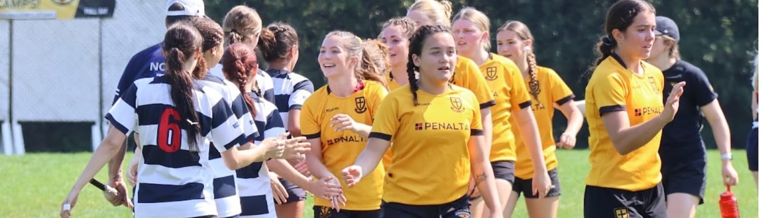 Rugby players from the Crusaders Rugby Club in Oakville, wearing yellow jerseys and black-and-white stripes, standing on a field.