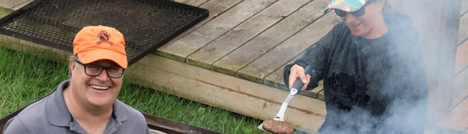 Two volunteers grilling outdoors at Crusaders Rugby Club in Oakville.