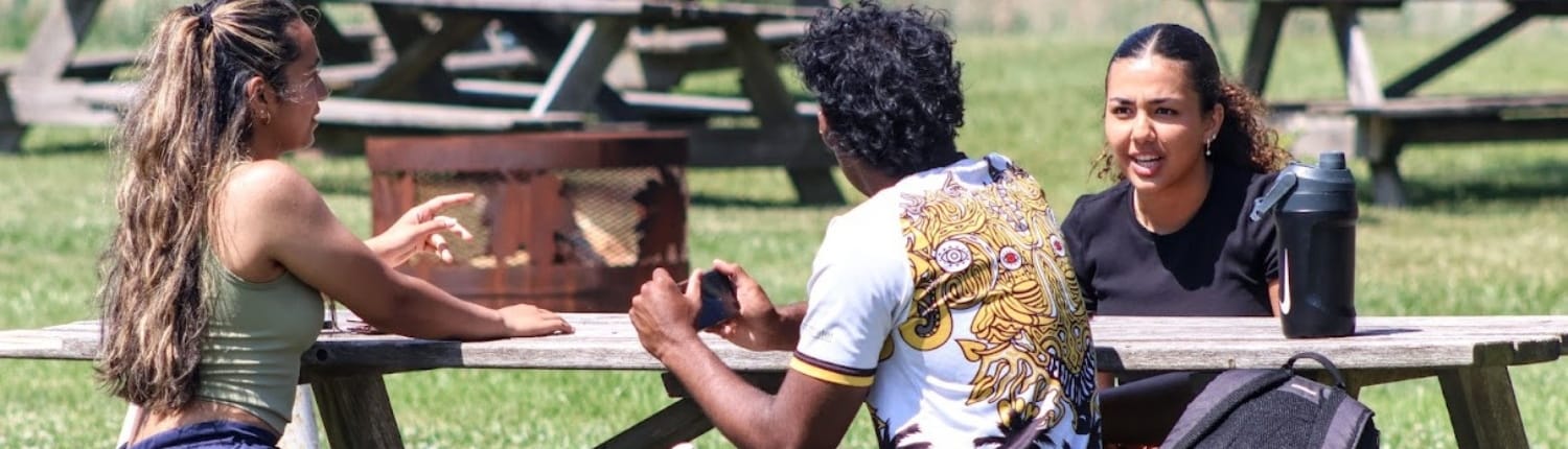 Beer Garden Crusaders Rugby Club players in Oakville pass a trophy at a picnic table in an outdoor park.