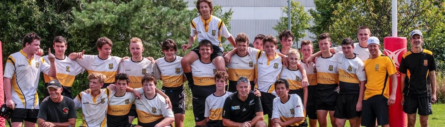 Group photo of Crusaders Rugby Club players in white jerseys posing together on a rugby field in Oakville.