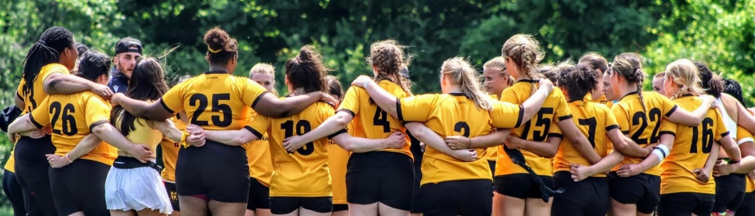 Crusaders Rugby Club players in yellow jerseys form a huddle on a grassy field in Oakville, with numbers visible on their backs.