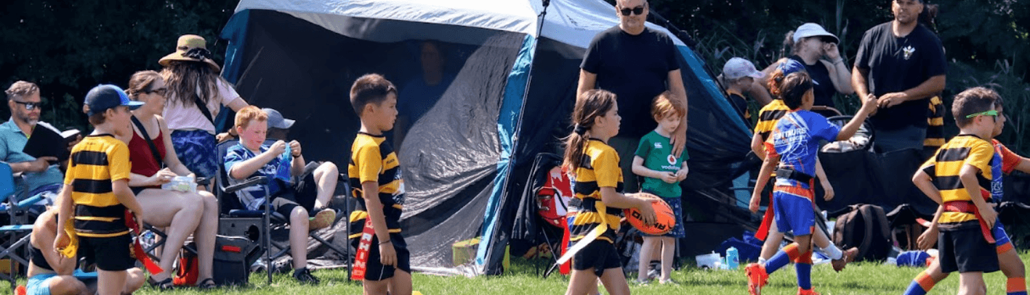 Kids Flag Rugby Game on Sunny Green Field Children playing flag rugby on a sunny field during a kids’ sports camp in Canada.