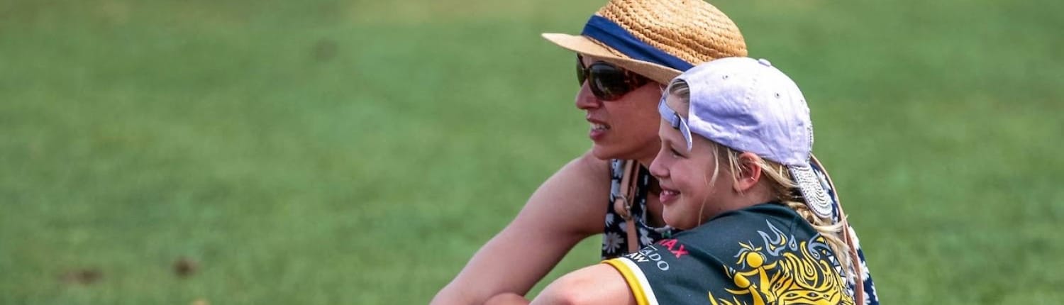 Two Crusaders Rugby Club members sit on the grassy field in Oakville.